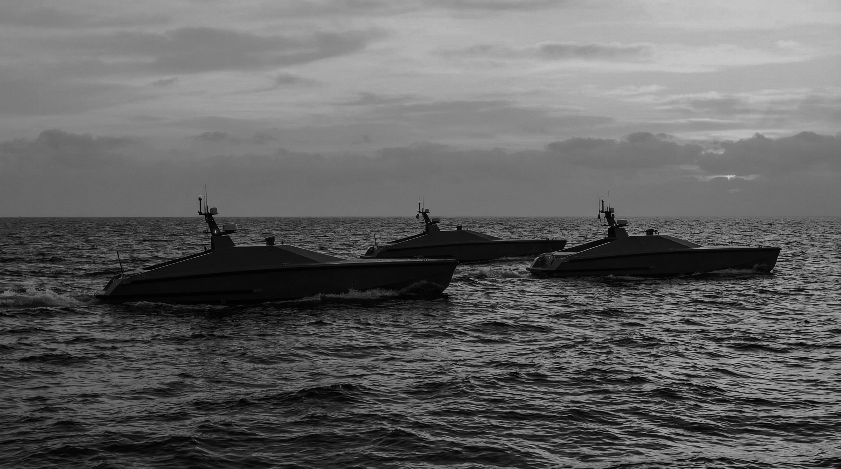 Three autonomous maritime craft crossing open water in formation