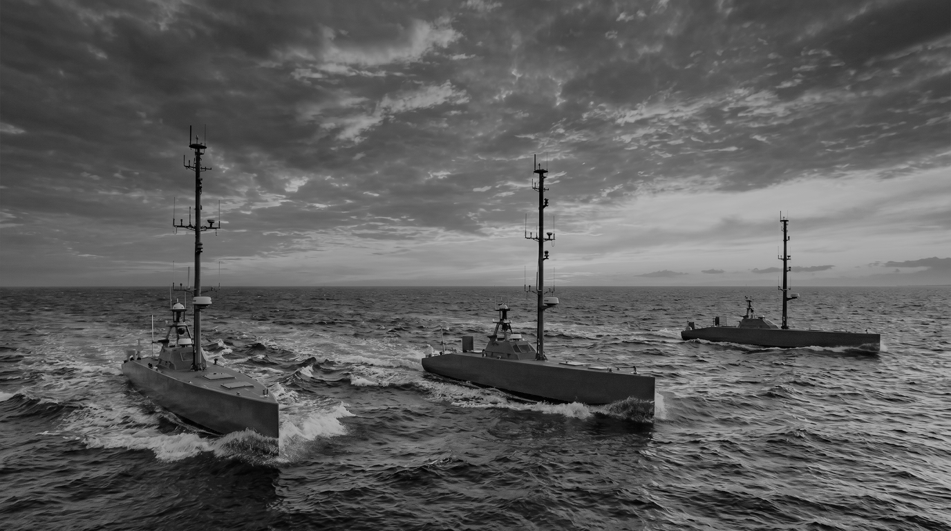 Three sleek dark autonomous surface vessels operating in formation across coastal water